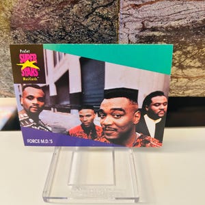 Può includere: Una carta collezionabile ProSet Super Stars Musicards con il gruppo Force M.D.'s. La carta ha uno sfondo verde acqua e viola con immagini dei quattro membri. La carta è esposta in un supporto di plastica trasparente.