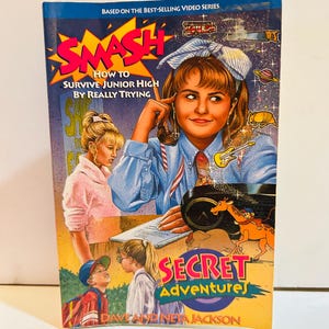 以下が含まれることがあります： デイブ＆ネータ・ジャクソン著『Secret Adventures』シリーズのペーパーバック『Smash: How to Survive Junior High by Really Trying』。表紙には、様々な小さなアイコンが描かれた生徒のイラストが中央に配置されています。