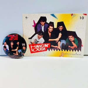 Puede incluir: Un botón y una tarjeta coleccionable con la banda New Kids on the Block. El botón tiene una foto de la banda con el texto "New Kids on the Block". La tarjeta coleccionable tiene una foto de la banda con el texto "Hangin' Tough" y el número "10."