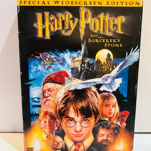 May include: A DVD case for "Harry Potter and the Sorcerer's Stone" in a special widescreen edition. The cover features Harry Potter, other characters, and a white owl. The title is in gold lettering.