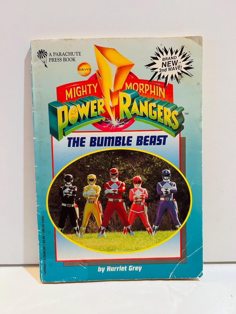 May include: A vintage paperback book titled "Mighty Morphin Power Rangers: The Bumble Beast." The cover features the Power Rangers in their signature colors, with the title in bold, 3D lettering. The book is by Harriet Grey.