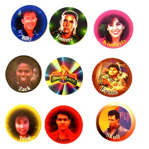 May include: Nine round, colourful, plastic buttons with images of the Mighty Morphin Power Rangers characters. The buttons feature the characters Billy, Tommy, Kimberly, Zack, Ernie, Trini, Jason, Skull, and the Mighty Morphin Power Rangers logo.