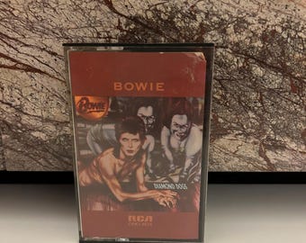 May include: A cassette tape with a red and black cover featuring a band called "BOWIE" and the album title "DIAMOND DOGS". The RCA logo and the catalog number "CPKT-0076" are visible on the tape.