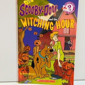 Puede incluir: Un libro infantil 'Scooby-Doo! y la Hora de las Brujas'. La portada muestra a Scooby-Doo, Shaggy y una escena de Halloween con calabazas y una bruja. Es un lector de nivel 2, publicado por Scholastic.