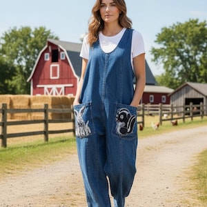 May include: A denim jumpsuit with embroidered animal pocket details. The blue jumpsuit features a white t-shirt underneath and white sneakers. The pockets are decorated with a rabbit and a skunk. The background includes a red barn and a wooden fence.
