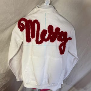 May include: White sweatshirt with a red fuzzy "Merry" applique on the back.