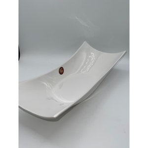 May include: White ceramic serving dish with a curved shape. The dish is made of high-quality porcelain and is perfect for serving appetisers, desserts, or snacks.
