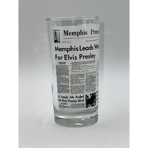 May include: A clear glass tumbler with a black and white newspaper print design. The newspaper headline reads "Memphis Leads World For Elvis Presley" and "A Lonely Life Ended On Elvis Presley Blvd."
