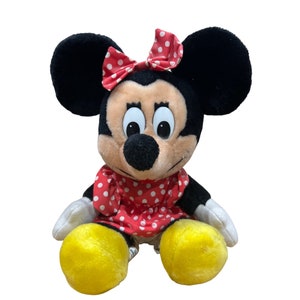 Pu&ograve; includere: Un giocattolo di peluche di Minnie Mouse, la fidanzata di Topolino. Indossa un vestito rosso con pois bianchi e un fiocco rosso con pois bianchi. Ha le orecchie nere e un naso nero.