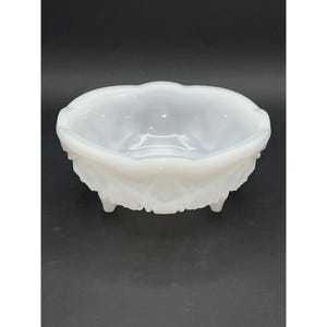 Puede incluir: Tazón de vidrio de leche blanco con un borde festoneado y un diseño decorativo en relieve. El tazón tiene tres patas.