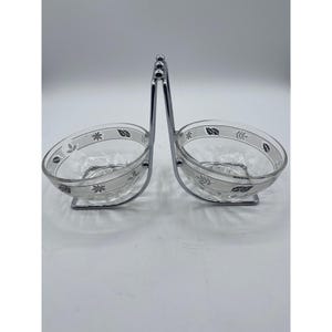 May include: A set of two clear glass bowls with a silver leaf design, on a chrome stand with a handle.