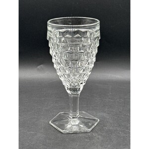 May include: A clear, vintage-style goblet with a textured, diamond-patterned bowl. The goblet has a hexagonal base and a slender stem. The rim of the glass is smooth. The glass is made of clear glass.
