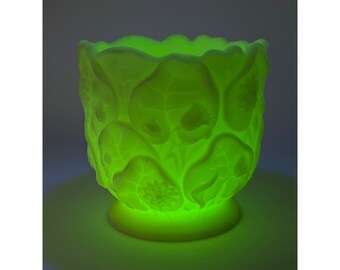 May include: A green ceramic planter with a leafy design. The planter is illuminated from within, casting a soft glow.