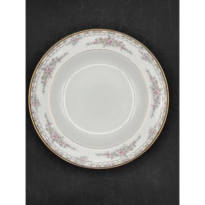 May include: A white porcelain soup bowl with a gold rim and a delicate floral pattern in shades of pink and gray.
