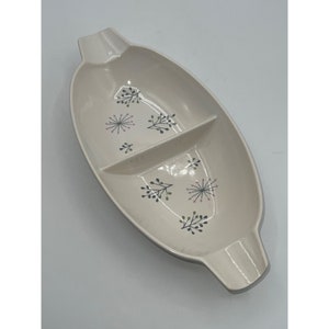 May include: A white divided serving dish with a floral design. The dish has two sections and a handle on each end.