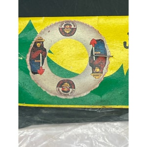 May include: A vintage Smokey Bear inflatable ring with a yellow, green, and white color scheme. The ring features a Smokey Bear image with the text "Smokey Bear" and "Prevent Forest Fires".