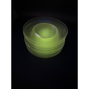 Op de afbeelding: Een stapel van 10 felgele glazen borden. De borden zijn helder en hebben een licht rimpel effect.