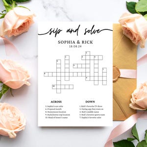 Peut inclure: Une carte de mots croisés blanche avec le texte "sip and solve" et "SOPHIA & RICK 18.08.24". La carte comprend des indices et des réponses. L'image est décorée de roses roses et d'une enveloppe dorée.
