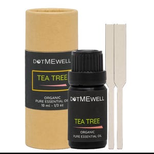 Könnte beinhalten: Eine braune Pappröhre mit einem schwarzen Etikett, auf dem "DOTMEWELL TEA TREE ORGANIC PURE ESSENTIAL OIL 10 ml - 1/3 oz" steht. Neben der Röhre befindet sich eine kleine dunkle Glasflasche mit einem schwarzen Etikett, auf dem "DOTMEWELL TEA TREE ORGANIC PURE ESSENTIAL OIL" steht. Zwei weiße Holzstäbchen befinden sich neben der Flasche.
