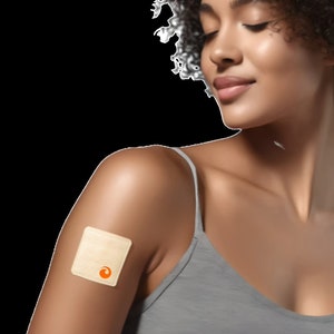 May include: A woman with short curly hair wearing a gray tank top has a beige square patch with an orange circle on her upper arm.