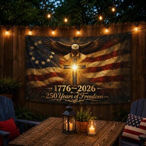 May include: A rectangular fabric banner featuring a distressed American flag background with a central glowing cross and a bald eagle with wings spread above it. The text 1776-2026 and 250 Years of Freedom is printed in gold lettering.