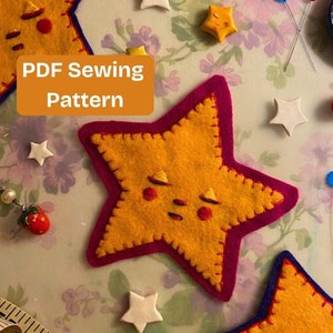 May include: PDF Sewing Pattern for a felt star with a cute face. The star is yellow with a pink border and a blue border. The star is surrounded by other felt stars, sewing pins, and a measuring tape.