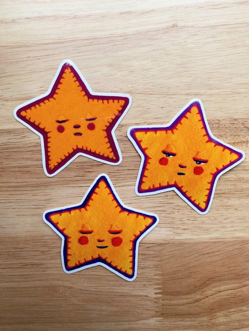 May include: Three yellow star-shaped stickers with embroidered edges and friendly faces. Each star has a different facial expression.