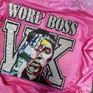 Puede incluir: Camiseta rosa con el texto "WORE' BOSS" y un gr&aacute;fico de la cara de una persona con una mano que la cubre parcialmente. La camiseta tambi&eacute;n tiene el texto "Vybz Kartel" y un dise&ntilde;o de estrella.