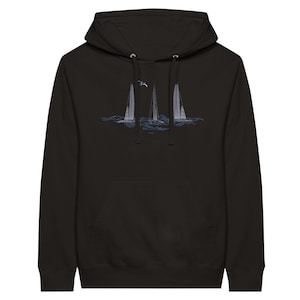 Puede incluir: Sudadera con capucha negra con un gráfico de tres veleros en un mar azul con una gaviota volando por encima.