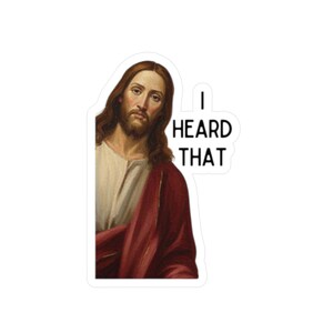Puede incluir: Una pegatina con un retrato de Jesús con pelo largo castaño y barba, vestido con una túnica blanca y una capa roja. El texto "I HEARD THAT" está en negro.