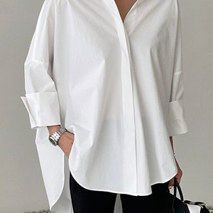 May include: A white oversized button-down shirt with long sleeves and a v-neck collar.