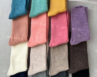 May include: A set of 12 pairs of ribbed socks in various colors, including teal, green, yellow, purple, pink, beige, brown, black, gray, and white.  The socks are folded and arranged in rows.  The text "Love Entity" is visible on a white tag.