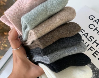Puede incluir: Un montón de ocho pares de calcetines de varios colores, incluyendo rosa, verde claro, beige, marrón, gris, negro y blanco. Los calcetines están hechos de un material suave y peludo.