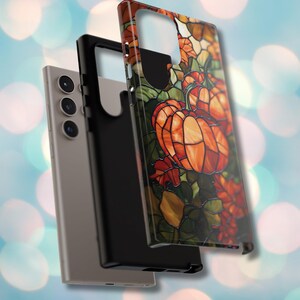 Puede incluir: Una funda para tel&eacute;fono con un dise&ntilde;o de vitral con calabazas y hojas en tonos naranja, rojo y verde.