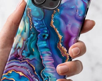 Puede incluir: Una funda para smartphone con un patrón abstracto vibrante y arremolinado en tonos azul profundo, morado y verde azulado, acentuado con finas líneas doradas metálicas que imitan la apariencia de capas de piedra ágata y texturas cristalinas.
