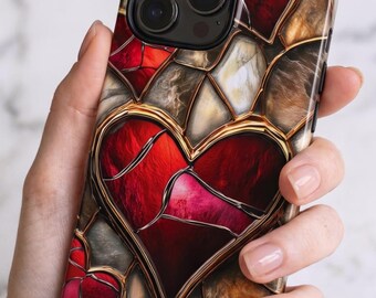 Puede incluir: Una funda para smartphone con un diseño de vidriera que presenta corazones de color rojo intenso y detalles en gris marmolado y dorado. El patrón consta de piezas segmentadas con bordes en oro metálico, creando un efecto de mosaico.