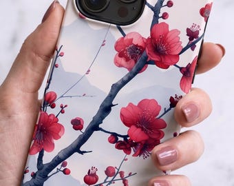May include: A smartphone case featuring a light cream background with a dark blue tree branch illustration. The branch is adorned with vibrant red and pink cherry blossom flowers. The design includes subtle, pale blue mountain silhouettes.