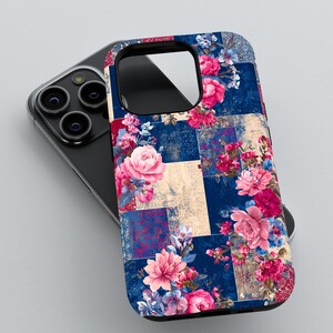 May include: A floral phone case with a patchwork design. The case features a navy blue background with squares of varying colors and textures. Pink and red roses and other flowers are scattered across the case.