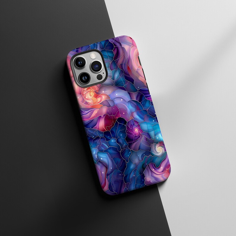 May include: A phone case with a colorful abstract design featuring swirling patterns in shades of blue, purple, pink, and gold. The design resembles stained glass with a galaxy-like theme.
