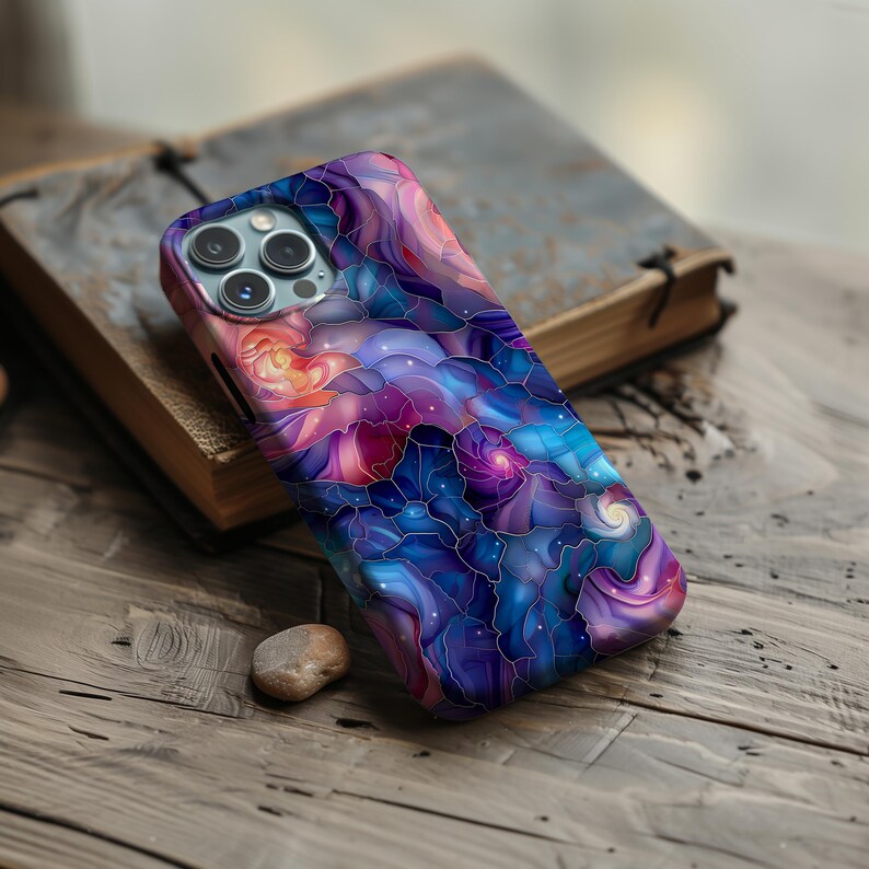 May include: A phone case with a colorful abstract design featuring swirling patterns in shades of blue, purple, pink, and orange. The design resembles stained glass with a galaxy theme.