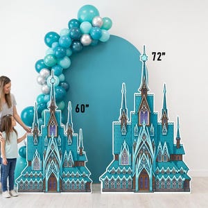 May include: Two cardboard cutouts of a teal and white castle, 60 and 72 inches tall, stand in front of a teal backdrop and a balloon arch. A woman and child stand near the castle cutouts.