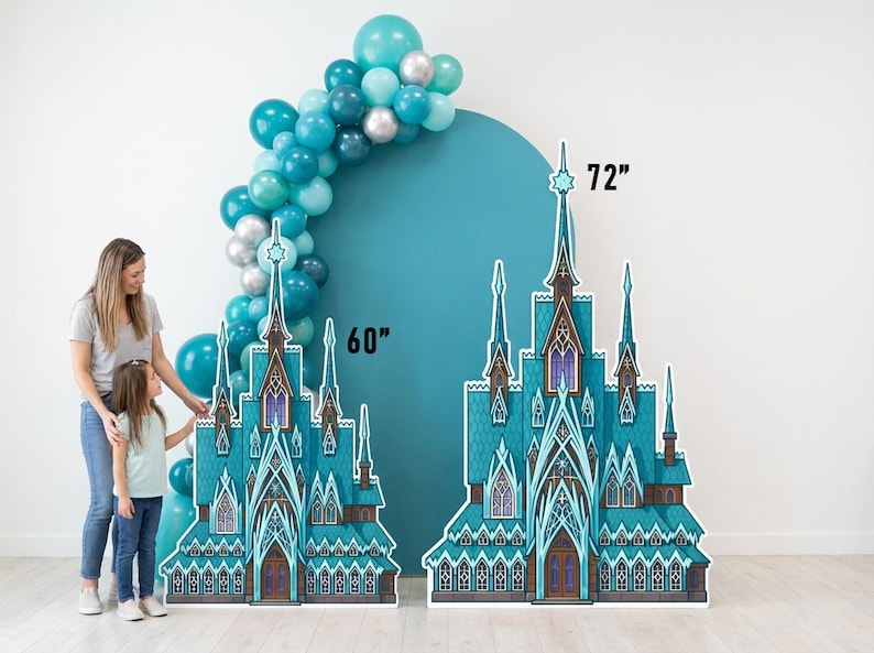 May include: Two cardboard cutouts of a teal and white castle, 60 and 72 inches tall, stand in front of a teal backdrop and a balloon arch. A woman and child stand near the castle cutouts.
