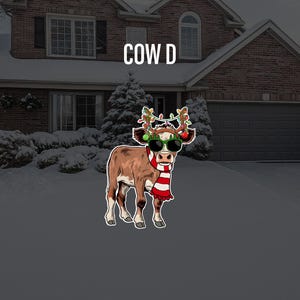 May include: A cartoon cow wearing a red and white striped scarf and sunglasses with a green and red garland on its head. The cow is standing in front of a house with a snowy driveway.