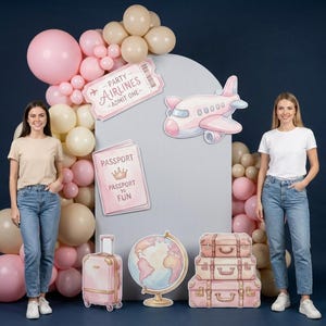 May include: A travel-themed party backdrop with pink and beige balloons, cutouts of a passport, airplane, globe, suitcase, and stacked luggage. The text "Party Airlines - Admit One" is visible on the ticket.