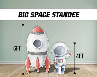 May include: A set of two cardboard stand-up figures for a space-themed party. The larger figure is a white and red rocket ship, measuring 6 feet tall. The smaller figure is a white astronaut with a blue visor, measuring 4 feet tall.  BIG SPACE STANDEE is written in black letters at the top of the image.