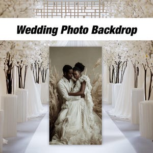 May include: A wedding photo backdrop with white fabric and white blossom branches. A couple is standing in the center of the backdrop, the woman is wearing a white dress and the man is wearing a white shirt and black pants.