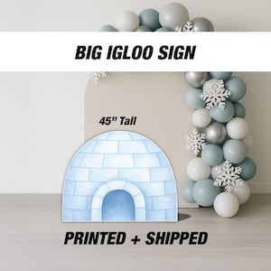 May include: A light blue igloo-shaped sign, 114 cm tall, with a rounded entrance. The sign is made of light blue bricks and has the text "BIG IGLOO SIGN" in bold black letters. White and silver balloons and snowflakes decorate the background.