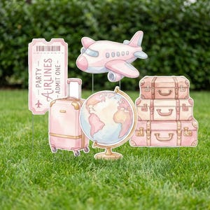 May include: Pink travel-themed garden decorations, including a ticket, airplane, suitcase, globe, and stacked luggage. The ticket reads "Party Airlines - Admit One". The decorations are set on a green lawn.