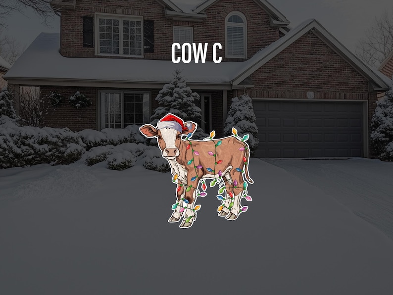 May include: A brown and white cow wearing a red Santa hat and wrapped in colorful Christmas lights. The cow is standing in front of a house with snow on the ground.