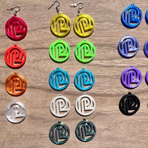May include: Assortment of colorful circle earrings with a geometric design. The earrings are made of plastic and have silver hooks.